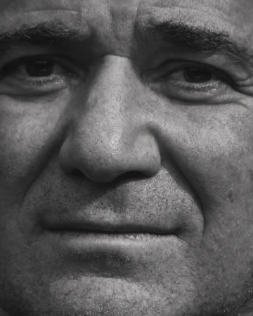 Monochrome extreme close-up portrait of a mature man's face showing detailed facial features and skin texture.