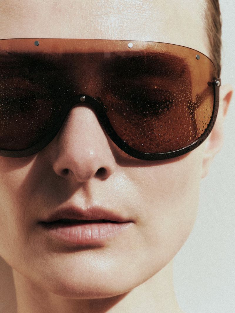 Close-up portrait of a model wearing large brown tinted shield sunglasses for Duel Magazine editorial