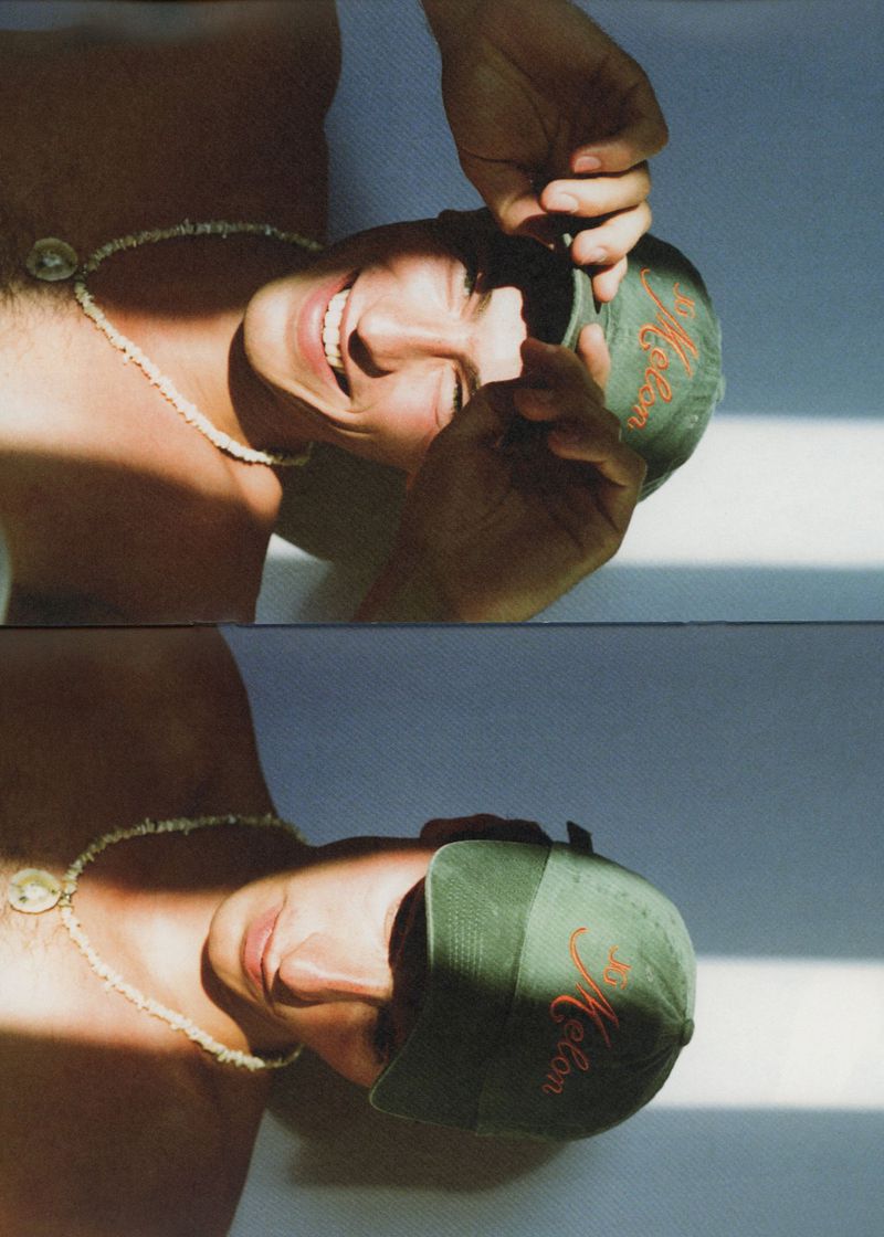 Two-panel vertical portrait of a shirtless man wearing a green baseball cap and shell necklace under striped sunlight shadows.