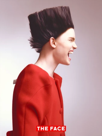 Side profile of model Malte Carlsson shouting in a bright red coat with an avant-garde flat-top hairstyle against a light grey background.