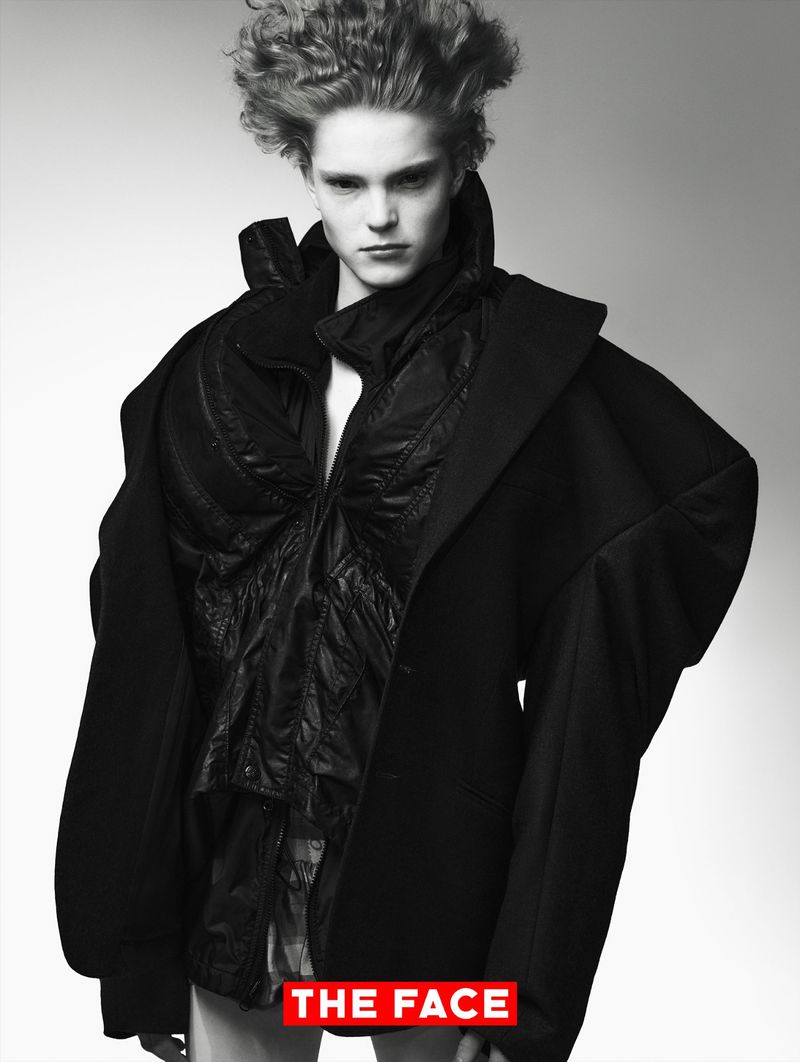 Model Malte Carlsson posing in sculptural layered black outerwear and tailored jacket against a light studio backdrop.