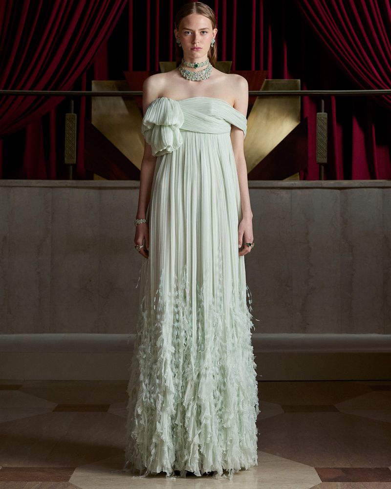 Model in pale green strapless gown wearing elaborate diamond and gemstone choker against red velvet drapes