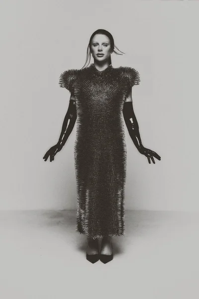 Model Bimini wearing a spiky textured midi dress and black latex gloves against a pale studio backdrop.
