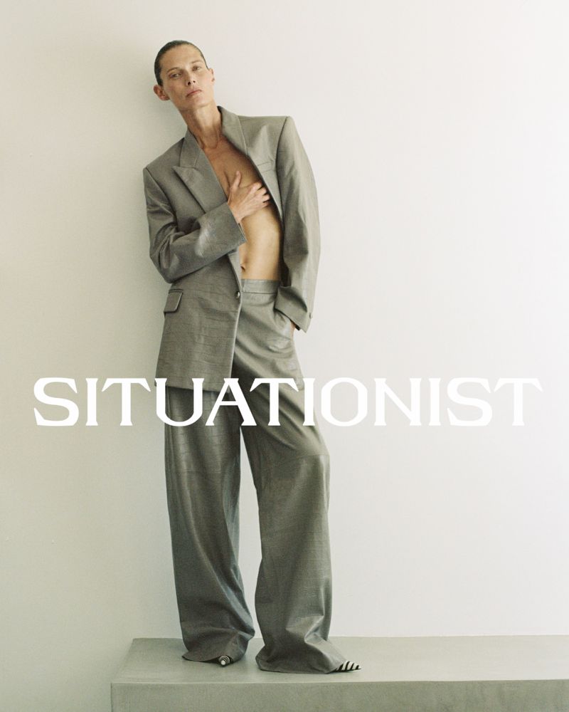 Model Malgosia Bela leaning against a wall wearing a grey suit jacket and matching trousers for Situationist