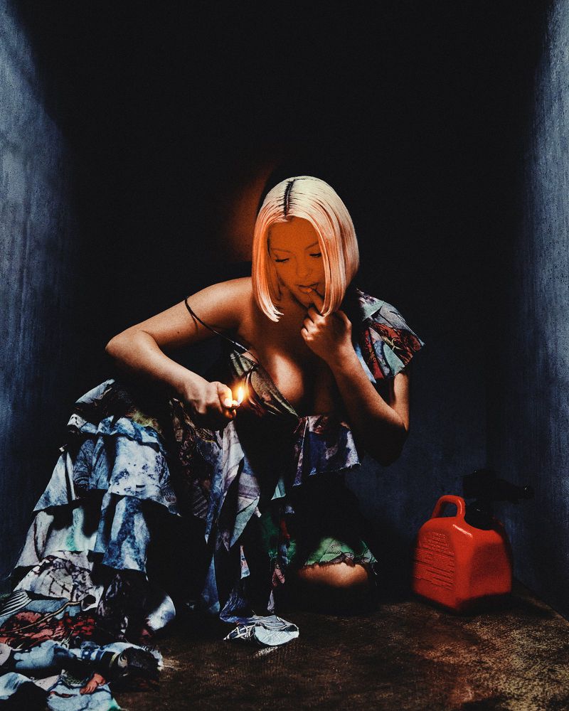 Bebe Rexha kneeling with a lit lighter wearing a tiered ruffled dress next to a red gas can in a dark room.
