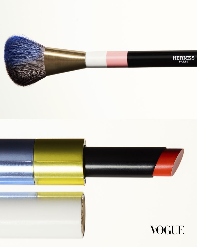 Close-up still life of a makeup brush and lipstick against a bright white background.