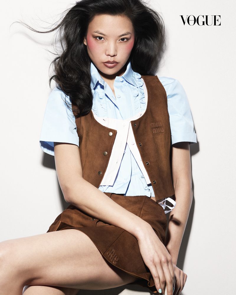 Model Xue Huizi wearing a brown vest and blue shirt against a white backdrop for Vogue Thailand