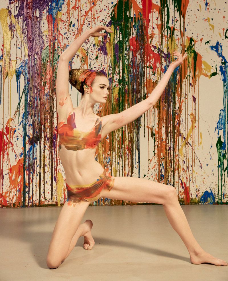 Dancer in painted pose against a backdrop of colorful dripping paint splatters