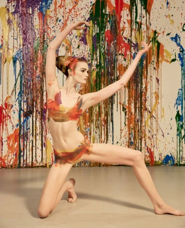 Dancer in painted pose against a backdrop of colorful dripping paint splatters
