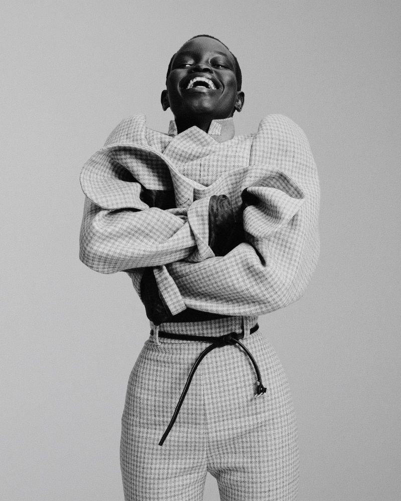 Model Athiec Geng wearing an exaggerated sculptural houndstooth jacket and trousers against a neutral studio backdrop.