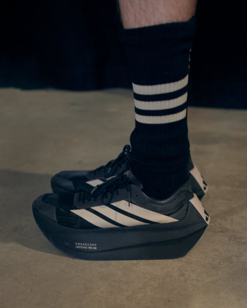 Close-up of black and off-white chunky platform sneakers and black striped socks on a studio floor.