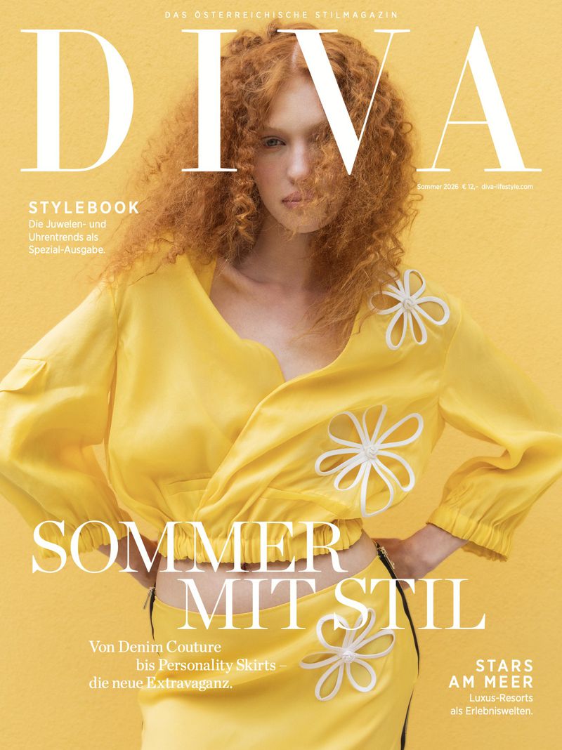 Model Julia Strege with curly red hair wearing a yellow top with white floral appliqués against a matching yellow backdrop.