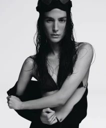 Model Mijo Mihaljcic with wet hair and diving goggles wearing a bikini top against a white studio background.