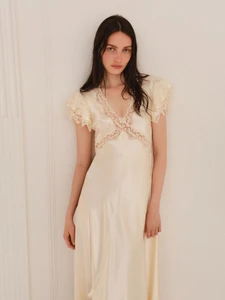 Model Clara Denison poses in an ivory lace-trimmed satin gown against a neutral wall for Alberta Ferretti Resort 2026.