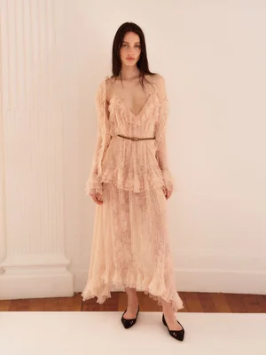 Model Clara Denison poses in a ruffled blush lace maxi dress and black pointed flats for Alberta Ferretti Resort 2026.