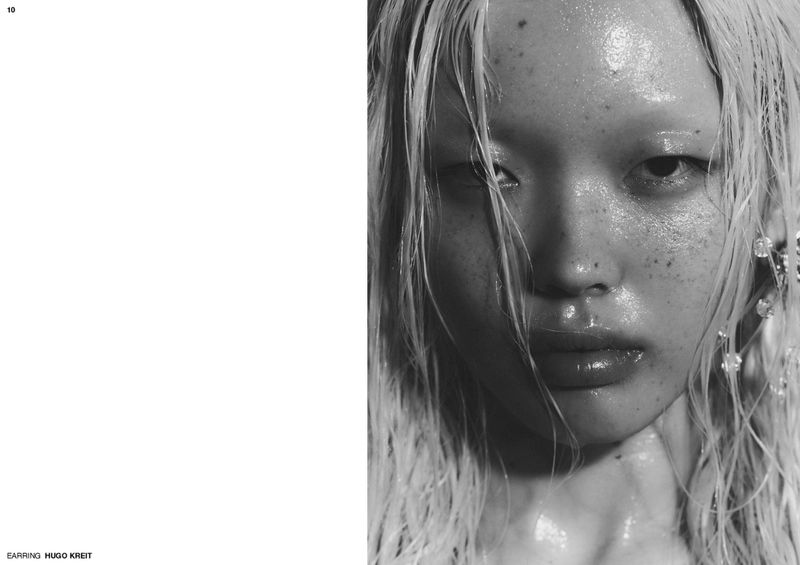 Black and white close-up editorial portrait of an Asian woman with wet hair and glossy skin next to a white magazine layout page.
