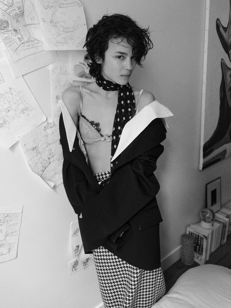Black and white portrait of model Gabrielle Rul wearing an off-the-shoulder blazer, polka-dot scarf, and houndstooth skirt.