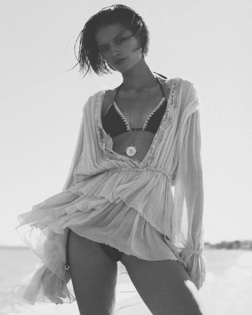 Model Bonnie Panasenko wearing a sheer ruffled tunic and bikini outdoors in a black and white editorial fashion portrait.