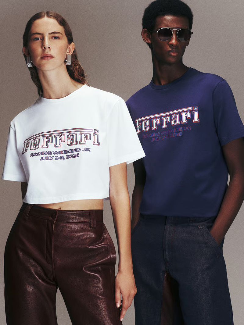 Two models posing in Ferrari graphic t-shirts and dark trousers against a neutral grey studio background.