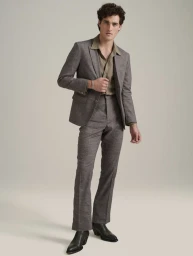 Full-length portrait of a male model wearing a grey suit jacket, matching trousers, and dark leather boots in a studio.