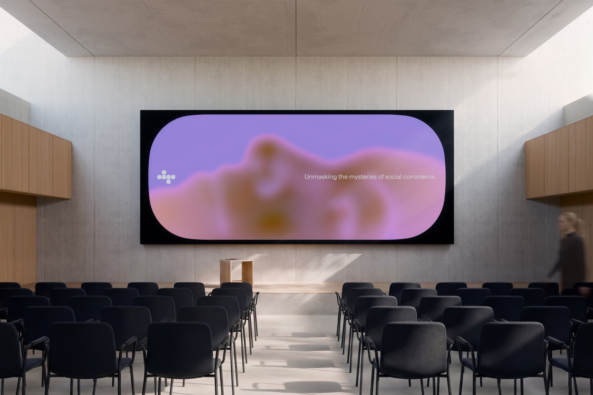 Modern minimalist auditorium with rows of black chairs facing a large presentation screen displaying purple abstract graphics.