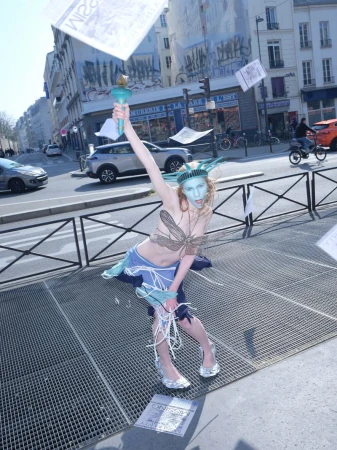 Model dressed as Statue of Liberty holding a torch on a city street with flying papers for Office Magazine editorial