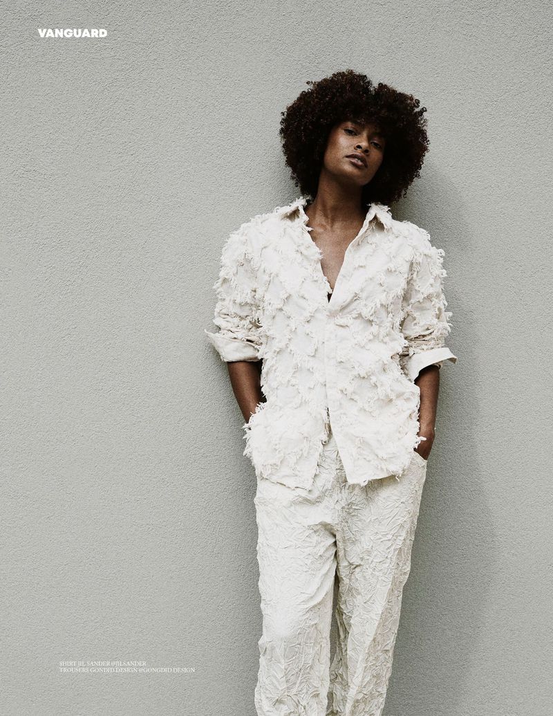 Black woman with an afro posing in a textured off-white fringed shirt and matching pants against a neutral background.