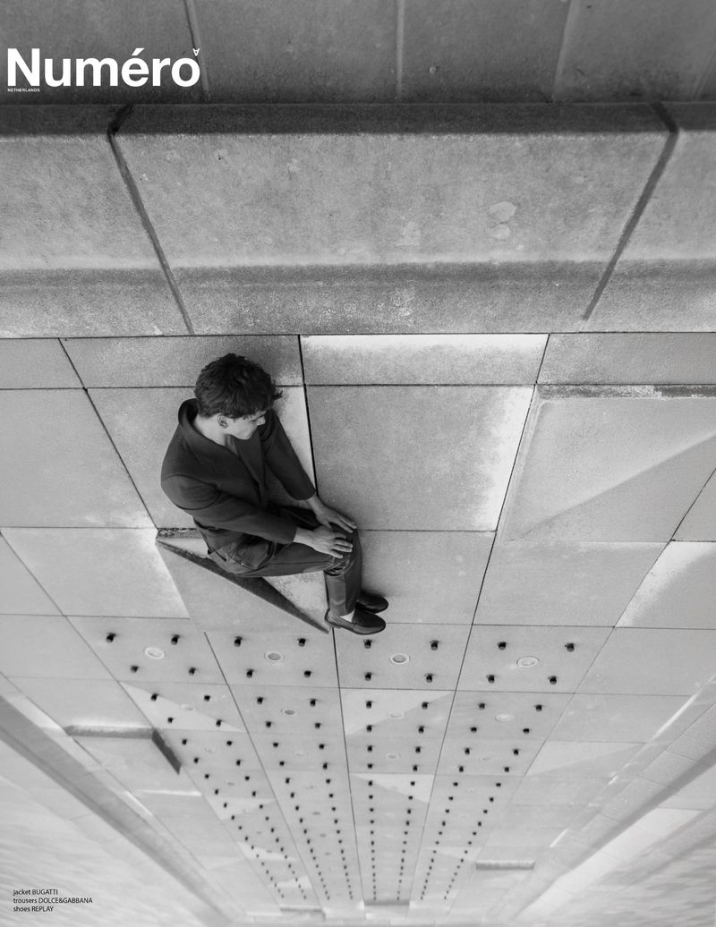 Model Dominik Schmidt seated on a geometric concrete architectural structure in black and white for Numéro Netherlands.