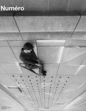 Model Dominik Schmidt seated on a geometric concrete architectural structure in black and white for Numéro Netherlands.