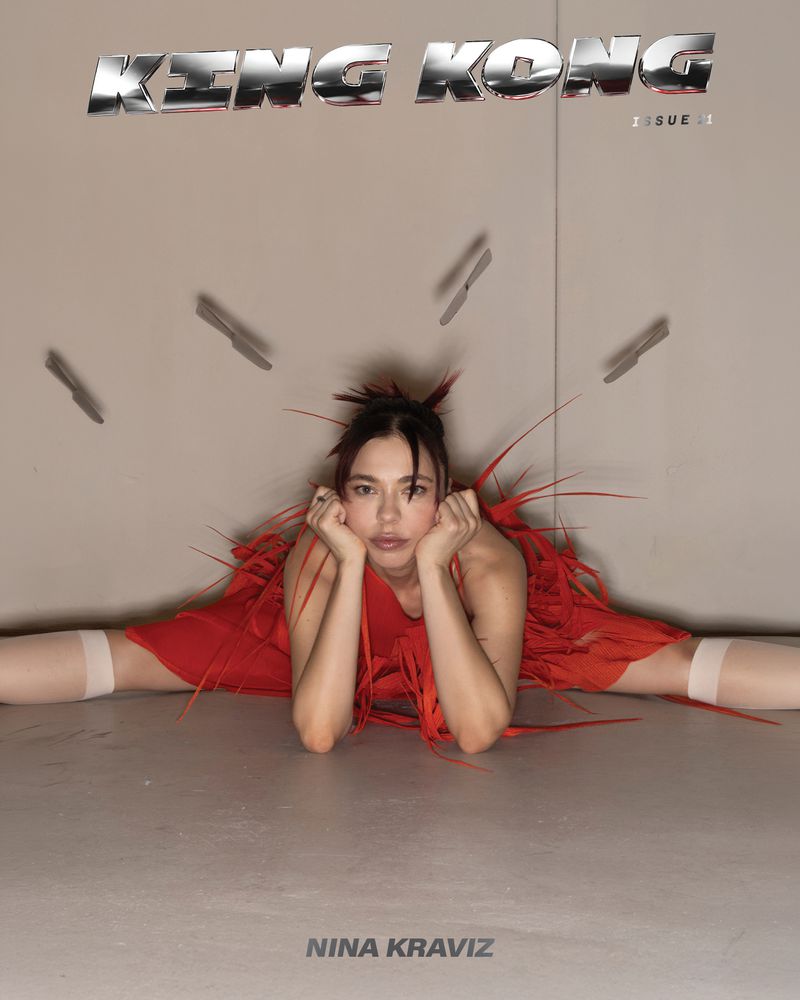 Nina Kraviz performing a leg split in a red fringe dress with floating chrome knives for King Kong Magazine.