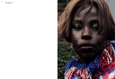 Editorial portrait of model Aweng Chuol with a brown bob hairstyle wearing a vibrant blue, red, and white knit scarf.