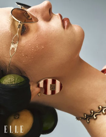 Close-up portrait of a woman wearing gold sunglasses and fruit tucked into dark hair for Elle China summer editorial
