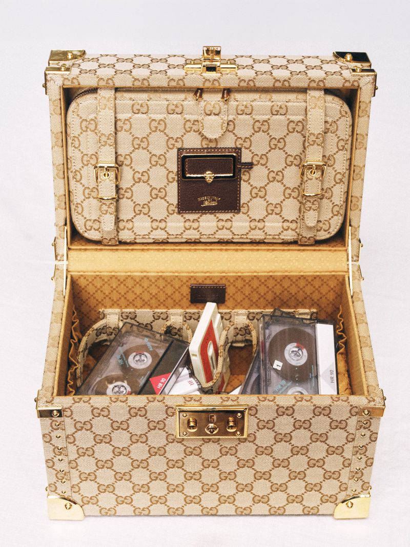 Open monogram vanity trunk filled with vintage cassette tapes against a white studio background.