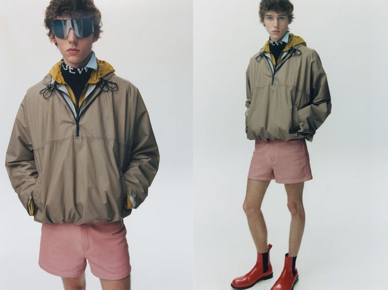 Male model wearing a tan hooded windbreaker and pink shorts against a white backdrop for Loewe lookbook.
