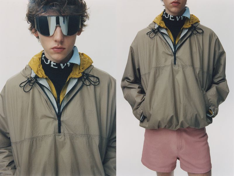 Model wearing a beige Loewe half-zip windbreaker, oversized shield sunglasses, and pink shorts against a pale background.