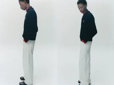 Two side-by-side shots of a young Black man standing in a black sweater with red trim, wide-leg off-white trousers, and black shoes.