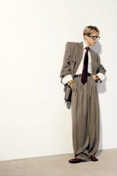 Troye Sivan wearing an oversized grey suit and dark tie against a plain white studio background for Vogue Australia.