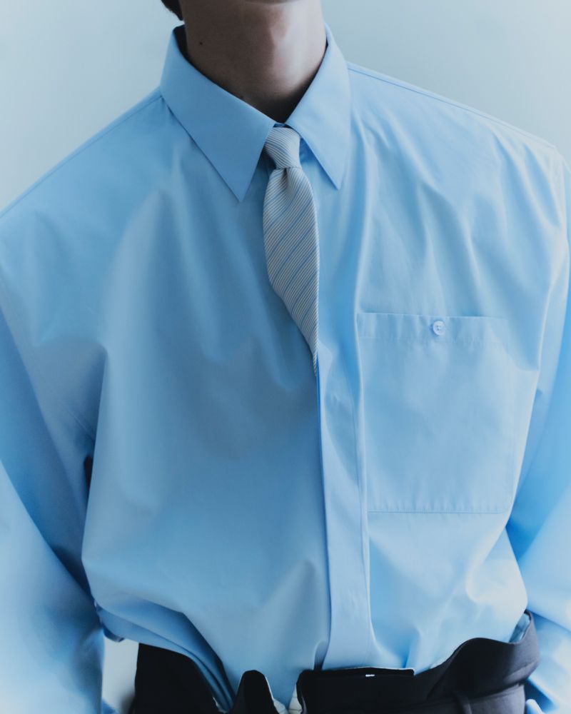 Close-up of a person wearing a light blue dress shirt and a striped necktie, showcasing fashion and formal wear.