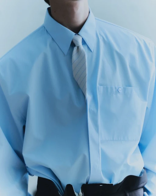 Close-up of a person wearing a light blue dress shirt and a striped necktie, showcasing fashion and formal wear.