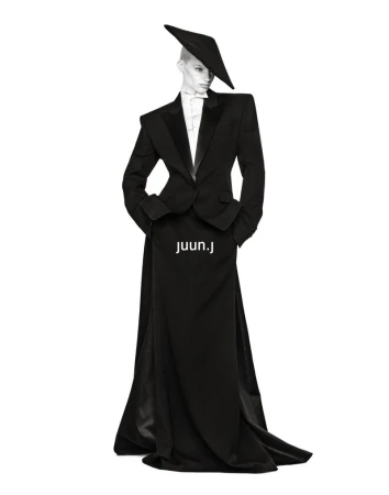 Mila van Eeten in a black structured tuxedo jacket, floor-length skirt, and angular hat against a white background for Juun.J.