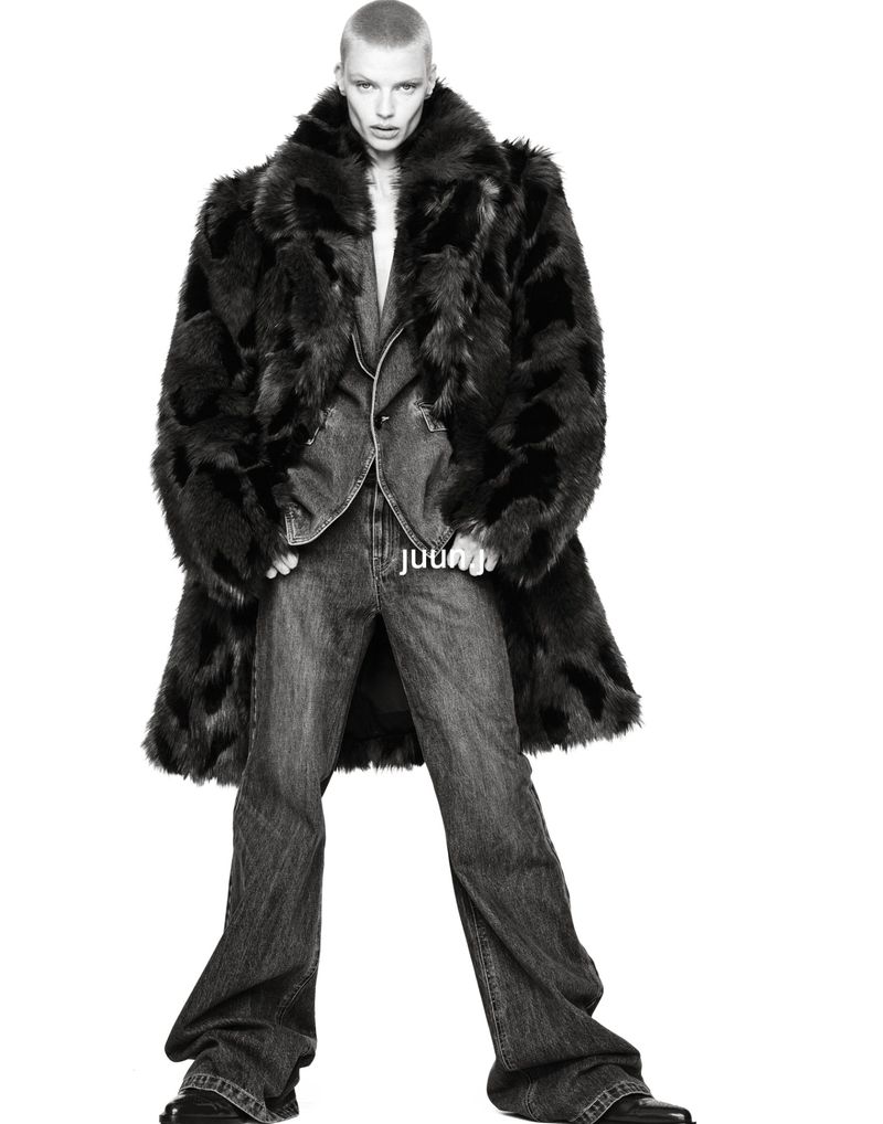 Model Mila van Eeten wearing a voluminous dark fur coat and wide-leg denim trousers against a clean white seamless studio background.