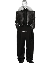Model Mila van Eeten wearing a shearling-collar leather jacket and wide-leg black trousers against a white seamless studio backdrop.