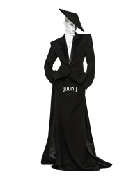 Mila van Eeten in a black structured tuxedo jacket, floor-length skirt, and angular hat against a white background for Juun.J.