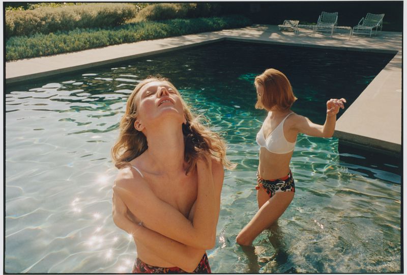 Two female models standing in a swimming pool during an outdoor editorial shoot for Vogue Ukraine.