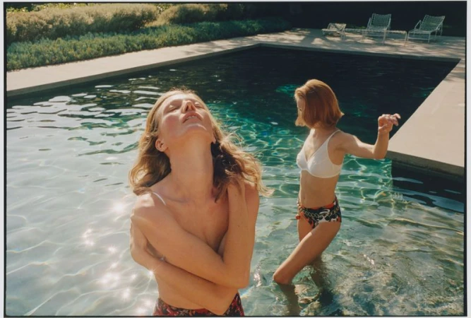 Two female models standing in a swimming pool during an outdoor editorial shoot for Vogue Ukraine.