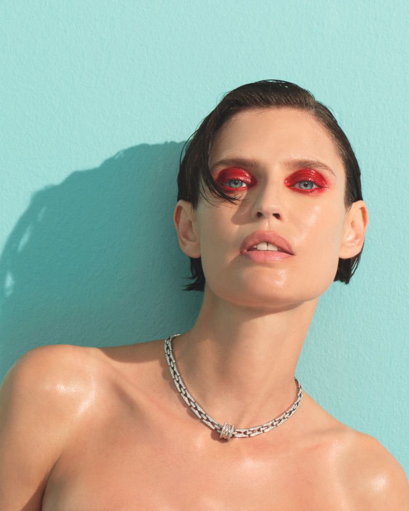Model Bianca Balti with glossy red eyeshadow and silver chain necklace against a turquoise backdrop for Harper's Bazaar Turkey.