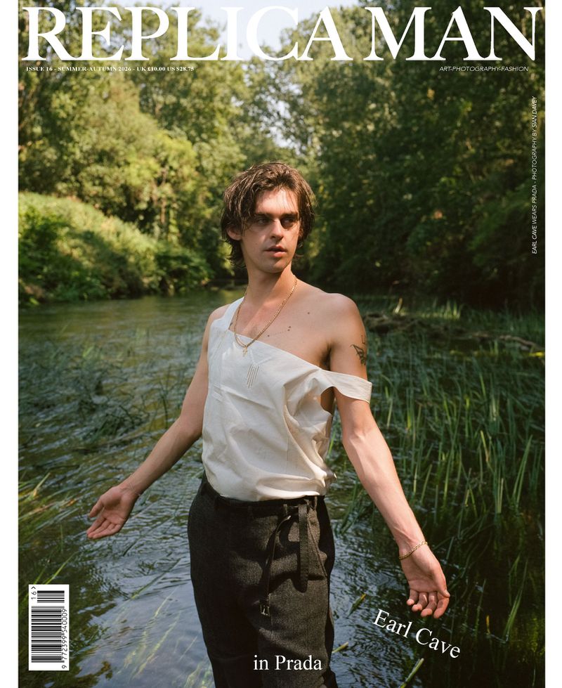 Magazine cover featuring actor Earl Cave standing in a river wearing an asymmetrical off-white top and dark trousers.