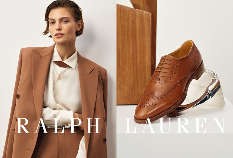Fashion editorial shot featuring a model in a brown suit next to a brown leather dress shoe on a platform for an ad campaign.