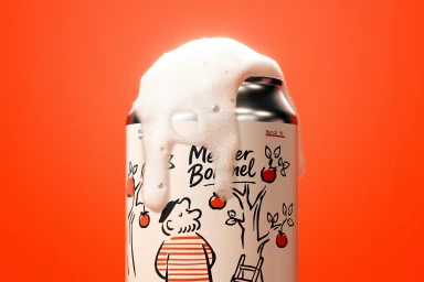 Overflowing white foam spills down a Meneer Bommel beverage can featuring an illustrated apple orchard against a solid red backdrop.