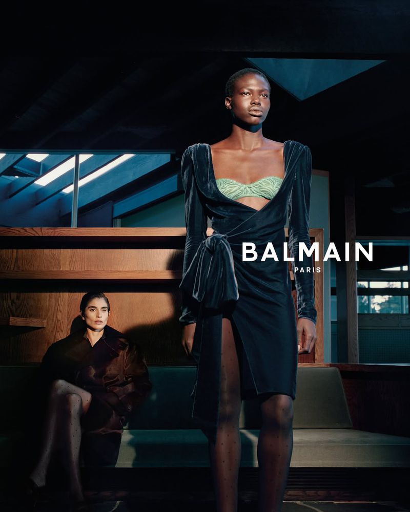 Model Abuk Yor standing in a black velvet wrap dress with a mint bustier for the Balmain F/W 2026 Campaign.